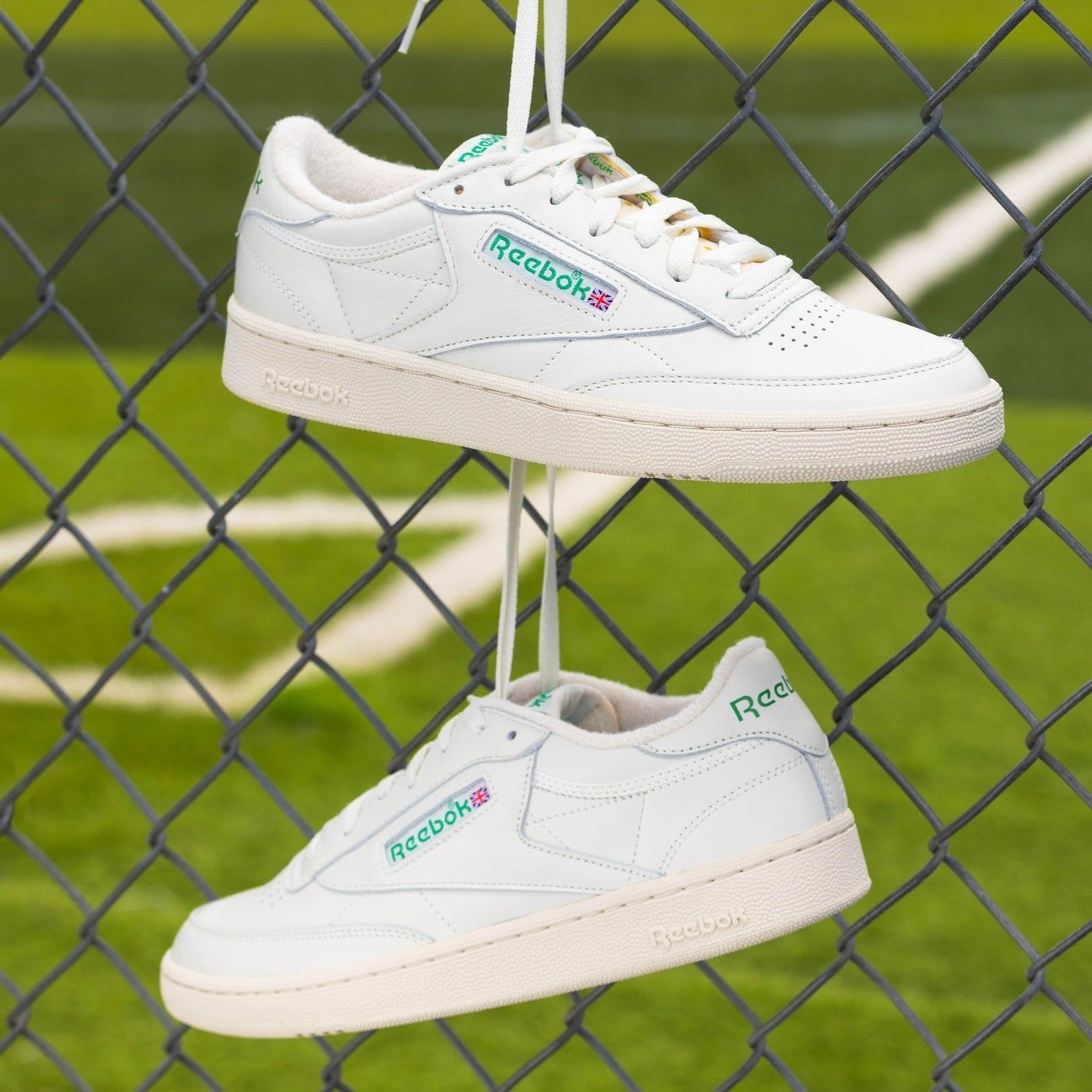 Side view of white and green Reebok tennis shoes.