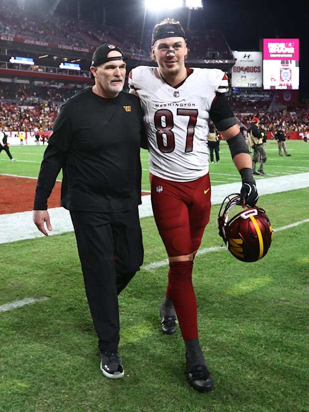 Washington Commanders head coach Dan Quinn celebrates with tight end John Bates (87).