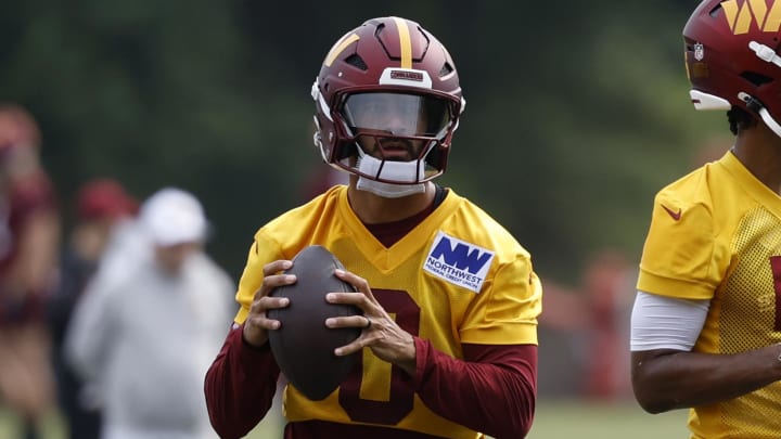 Jul 25, 2024; Ashburn, VA, USA; Washington Commanders quarterbacks Marcus Mariota (0) and Jayden Daniels (5) drop back to pass a ball during drills on day two of Commanders training camp at OrthoVirginia Training Center at Commanders Park. Mandatory Credit: Geoff Burke-USA TODAY Sports