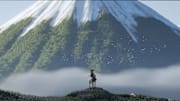 Ghost of Yotei - Atsu sits on horseback in the shadow of Mount Yotei