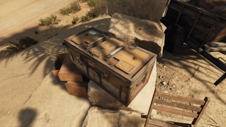 A chest by a tree in the middle of the desert.
