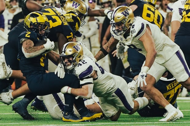 Carson Bruener (42) and Bralen Trice (8) converge on Michigan running back Blake Corum.