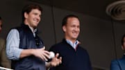 May 4, 2014; Bronx, NY, USA; New York Giants quarterback Eli Manning and Denver Broncos quarterback Peyton Manning watch the game between the New York Yankees and Tampa Bay Rays at Yankee Stadium. 