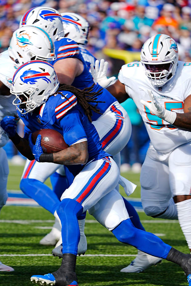 Bills James Cook slides past players for several yards with the ball with Miami's Benito Jones