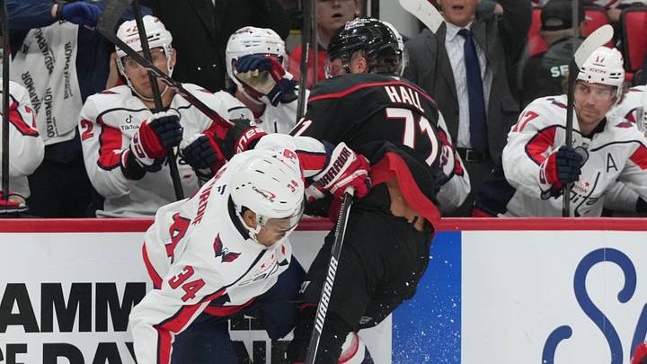 Oct 13, 2026; Raleigh, North Carolina, USA; Washington Capitals center Justin Sourdif (34) checks Carolina Hurricanes left wing Taylor Hall (71) during the first period at Lenovo Center.  Mandatory Credit: James Guillory-Imagn Images