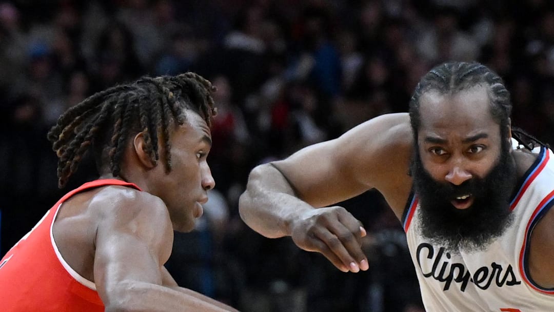Los Angeles Clippers guard James Harden dribbles the ball past Toronto Raptors guard Ja'Kobe Walter.