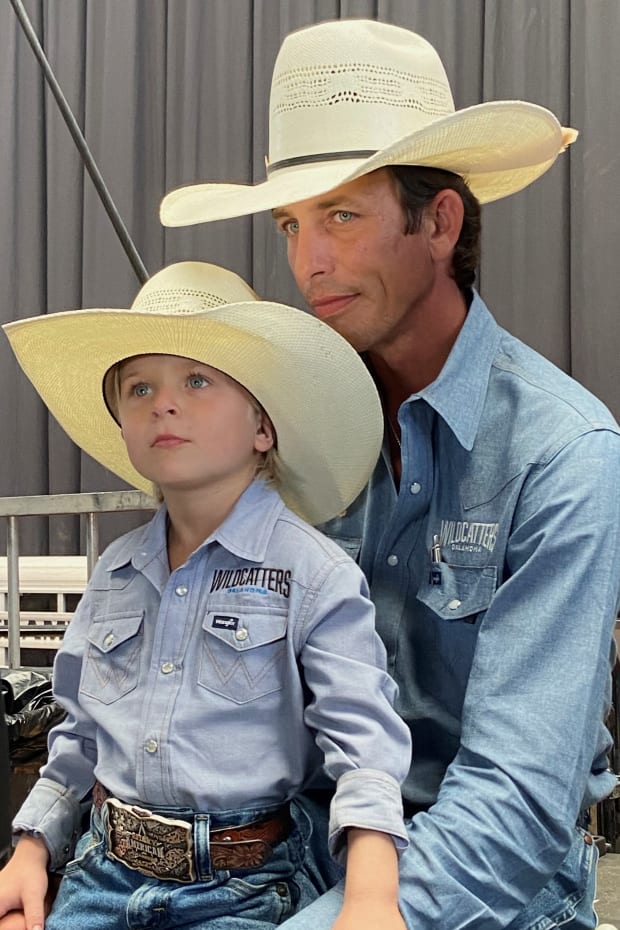 JB Mauney sits with his young son. Both wearing cowboy hats.