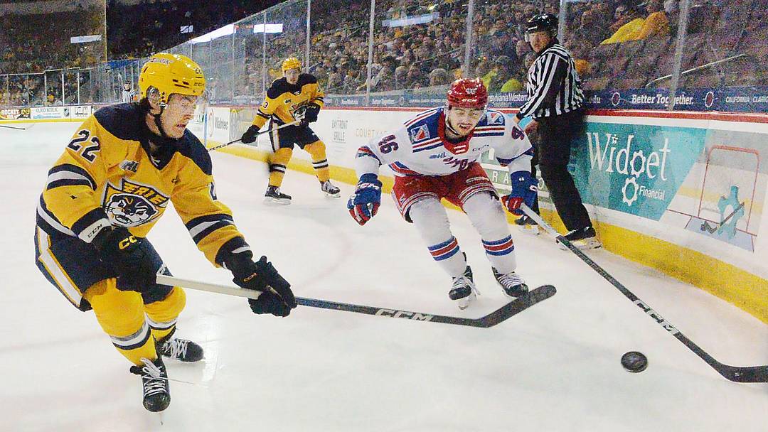 Erie Otters defenseman Spencer Sova, left, skates near Kitchener Rangers defenseman Simon Motew at Erie Insurance Arena in Erie on April 2, 2024.