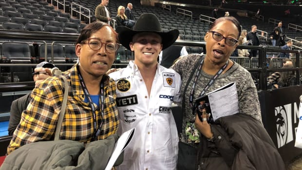 Two ladies standing with Cooper Davis, a bull rider.