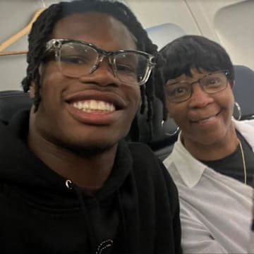 Travis Hunter sits next to Sandy Combs on an airplane.