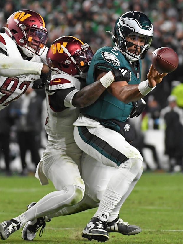 Eagles quarterback Jalen Hurts (1) throws a pass while being pressured by Washington Commanders safety Quan Martin.