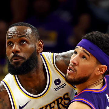 Feb 25, 2024; Phoenix, Arizona, USA; Los Angeles Lakers forward LeBron James (23) and Phoenix Suns guard Devin Booker (1) go for the ball during the second quarter at Footprint Center. Mandatory Credit: Mark J. Rebilas-USA TODAY Sports