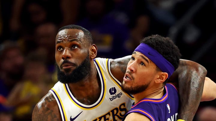 Feb 25, 2024; Phoenix, Arizona, USA; Los Angeles Lakers forward LeBron James (23) and Phoenix Suns guard Devin Booker (1) go for the ball during the second quarter at Footprint Center. Mandatory Credit: Mark J. Rebilas-USA TODAY Sports