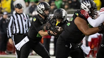 Oregon quarterback Brock Thomas, left, hands off the ball to running back Jordon Davison as the Oregon Ducks host the Wisconsin Badgers on Oct. 25, 2025, at Autzen Stadium in Eugene, Oregon.
