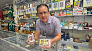 George Pepdjonovic holds baseball cards featuring Ken Griffey Jr., left, and Ted Williams at his George Pep's Baseball Card Shop in Quincy 