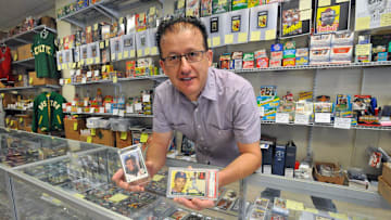 George Pepdjonovic holds baseball cards featuring Ken Griffey Jr., left, and Ted Williams at his George Pep's Baseball Card Shop in Quincy 