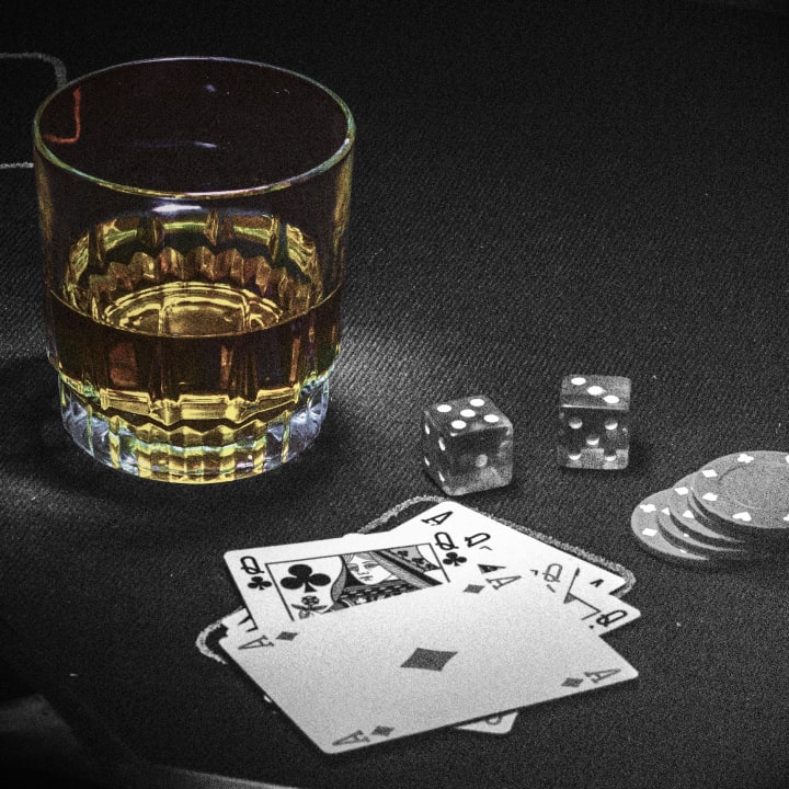 Glass of whiskey, cards, dice, and chips on a table