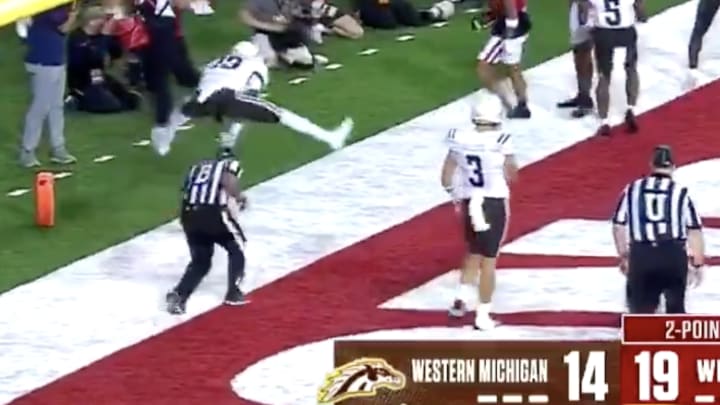 Western Michigan player leapfrogs referee during Wisconsin game.