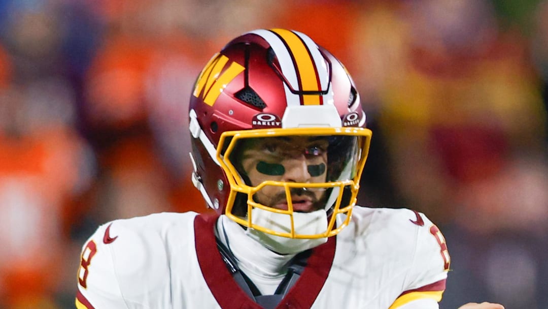 Washington Commanders quarterback Marcus Mariota scrambles with the ball against the Denver Broncos.