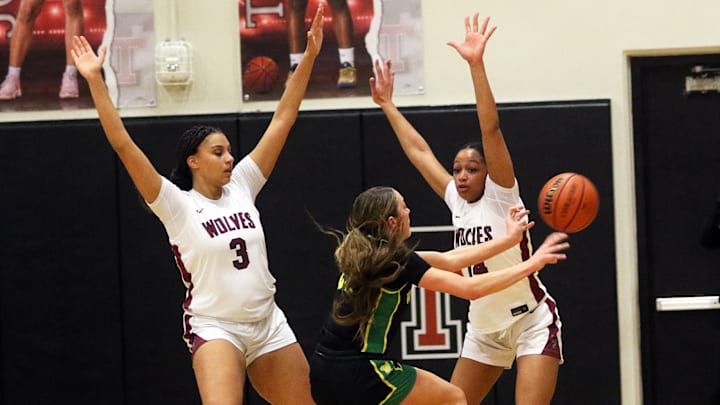 Tualatin senior Jordyn Smith (left) and junior Maaya Lucas put pressure on West Linn’s Kaylor Buse during a Three Rivers League showdown.