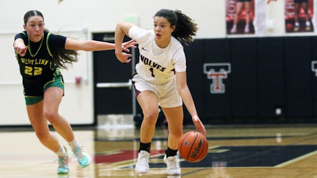 Tualatin freshman point guard Love Lei Best brings the ball up court against West Linn sophomore Kaylor Buse.