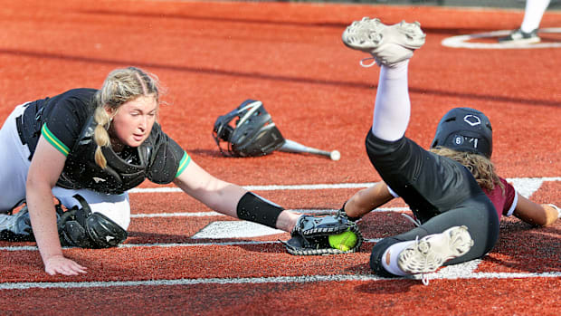Sherwood junior Daisha Cornwell (right) avoids the tag of West Linn junior catcher Piper Ruthrauff to score.