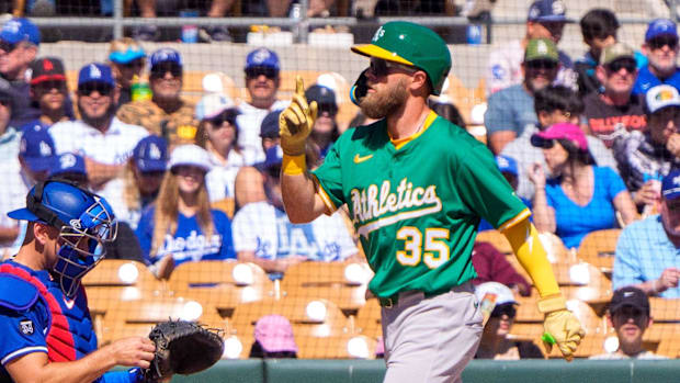 Athletics outfielder Drew Avans celebrates a home run in spring training, wearing a green and yellow helmet and jersey.