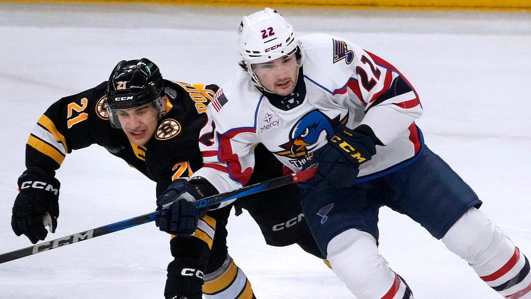 PBruin Matthew Poitras reaches in for the puck on Thunderbird Dylan Peterson in the first period.
