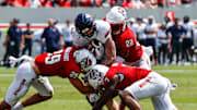 Sep 6, 2025; Raleigh, North Carolina, USA; Virginia Cavaliers tight end Sage Ennis (0) is tackled by North Carolina State Wolfpack safety Brody Barnhardt (29), cornerback Brian Nelson II (7) and cornerback Jackson Vick (22) during the first half of the game at Carter-Finley Stadium. Mandatory Credit: Jaylynn Nash-Imagn Images
