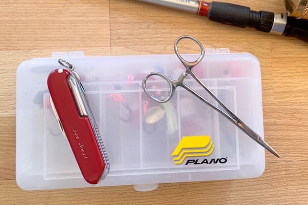 A telescopic fishing rod, a reel, a knife, and a small tackle box for fishing while camping.