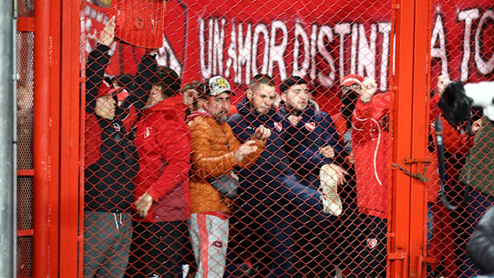 Aficionados de Independiente patean una puerta del estadio Libertadores de América en busca de evitar el caos en la tribuna.