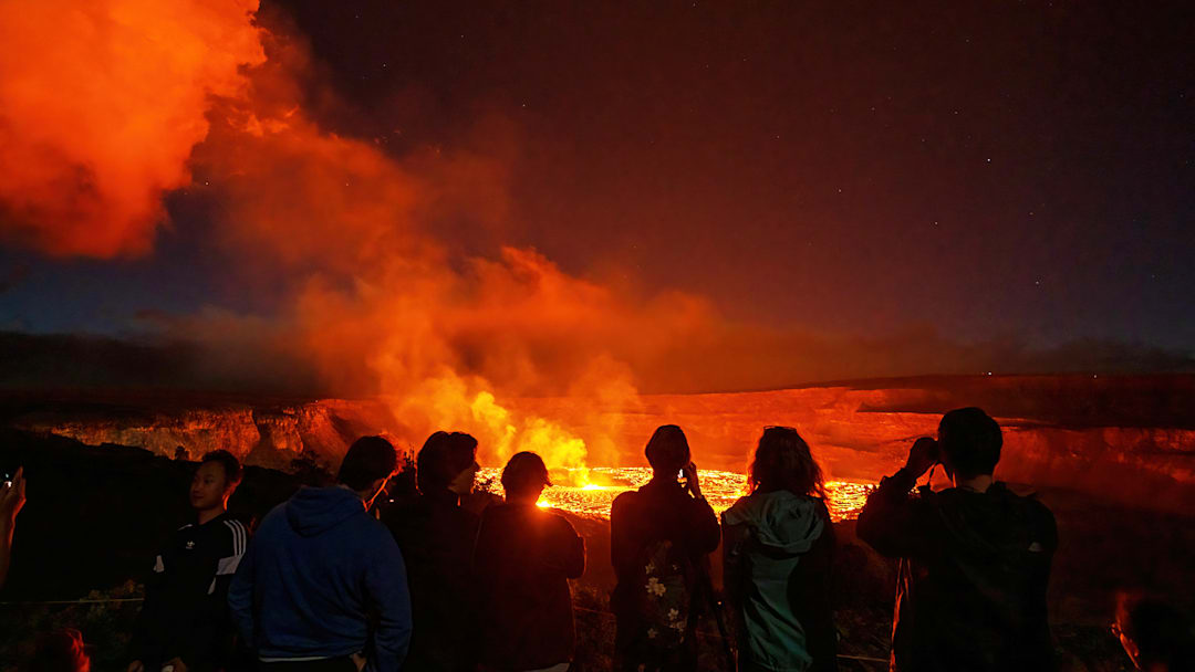 Hikers watch Kīlauea erupt from the safety of the trail. Hikers watch Kīlauea erupt from the safety of the trail.
