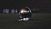 A high school football helmet sits on a field.