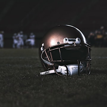 A high school football helmet sits on a field.