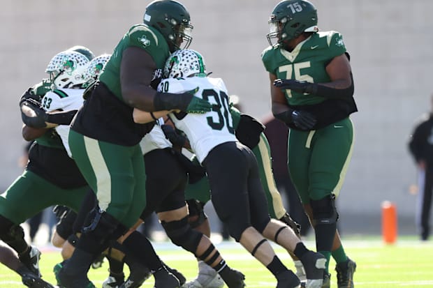 DeSoto's Byron Washington (left) swallows a pass rusher against Southlake Carroll in the Texas (UIL) 6A Division II semis.