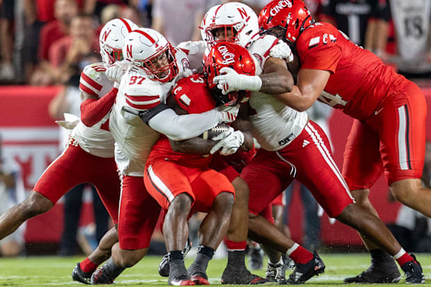 Cincinnati running back Tawee Walker is stopped for no gain by Nebraska defensive linemen Keona Davis and Cameron Lenhardt.