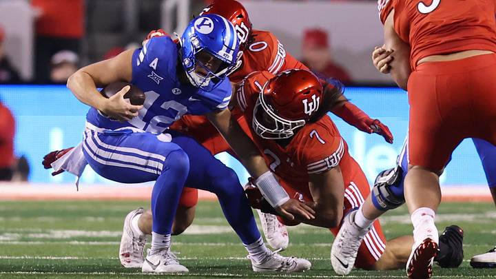 Nov 9, 2024; Salt Lake City, Utah, USA; Brigham Young Cougars quarterback Jake Retzlaff (12) is tackled by Utah Utes defensive end Logan Fano (0) and defensive end Van Fillinger (7) during the first quarter at Rice-Eccles Stadium. Mandatory Credit: Rob Gray-Imagn Images