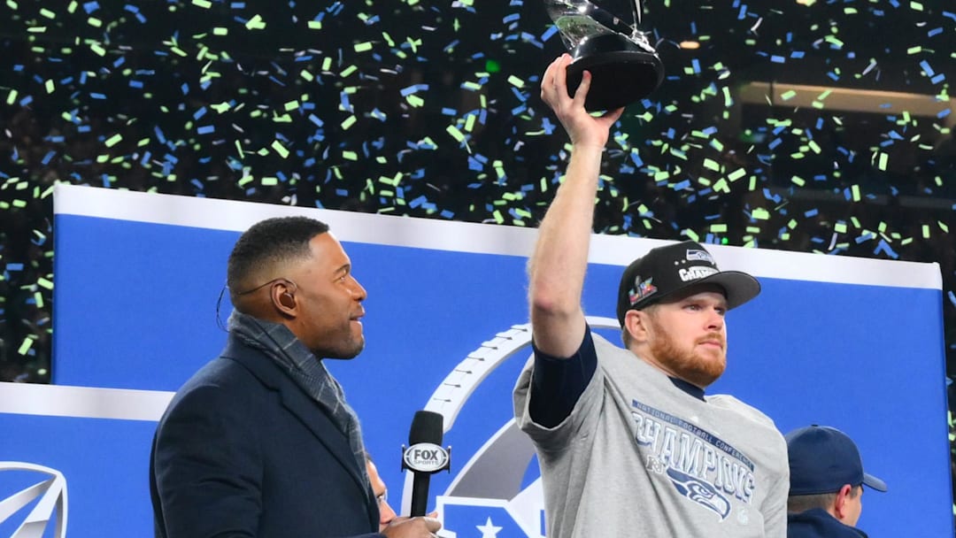 Jan 25, 2026; Seattle, WA, USA; Seattle Seahawks quarterback Sam Darnold (14) celebrates with the trophy on the podium after defeating the Los Angeles Rams in the 2026 NFC Championship Game at Lumen Field. Mandatory Credit: Steven Bisig-Imagn Images