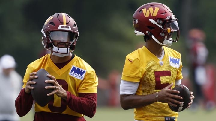 Jul 25, 2024; Ashburn, VA, USA; Washington Commanders quarterbacks Marcus Mariota (0) and Jayden Daniels (5) drop back to pass a ball during drills on day two of Commanders training camp at OrthoVirginia Training Center at Commanders Park. Mandatory Credit: Geoff Burke-USA TODAY Sports