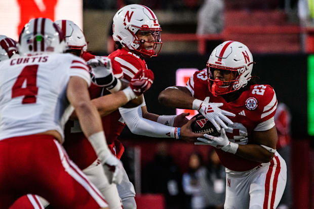 Dylan Raiola (15) hands the ball off to Dante Dowdell (23). 