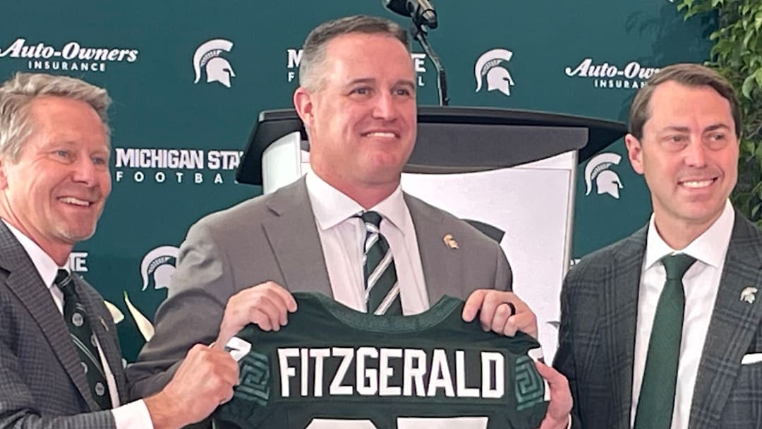 Michigan State Spartans head coach Pat Fitzgerald, center, poses with a namesake jersey next to MSU president Kevin Guskiewicz, left, and athletic director J Batt, right, during Fitzgerald's introductory press conference on Tuesday, Dec. 2, 2025.