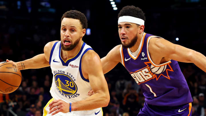 Dec 12, 2023; Phoenix, Arizona, USA; Golden State Warriors guard Stephen Curry (30) drives to the basket against Phoenix Suns guard Devin Booker (1) during the fourth quarter at Footprint Center. 