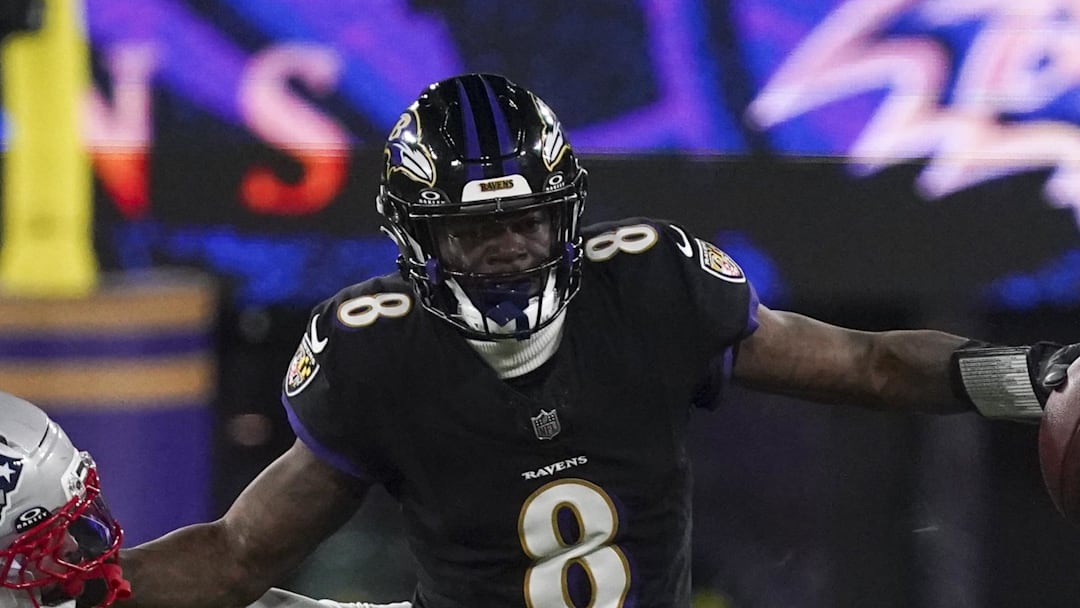 Baltimore Ravens quarterback Lamar Jackson stiff arms New England Patriots linebacker K'Lavon Chaisson.