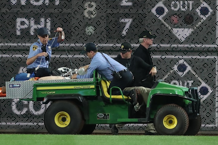 Pittsburgh Pirates medical personnel cart a fan who fell from the stands to the field to an ambulance.