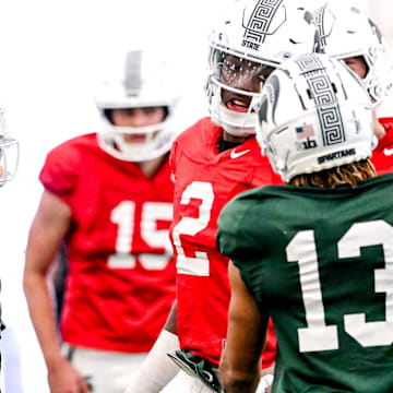 Michigan State quarterback Aidan Chiles, center, talks with receivers Chrishon McCray, right, and Nick Marsh during football practice on Tuesday, April 8, 2025, in East Lansing.