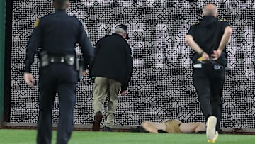 Stadium security and Pittsburgh Pirates medical personnel rush to assist a fan who fell from the stands to the field as the Pirates batted against the Chicago Cubs during the seventh inning at PNC Park. 
