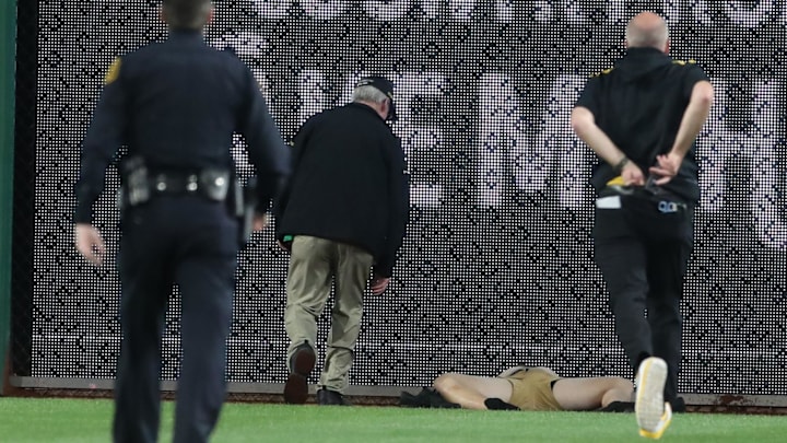 Stadium security and Pittsburgh Pirates medical personnel rush to assist a fan who fell from the stands to the field as the Pirates batted against the Chicago Cubs during the seventh inning at PNC Park. 