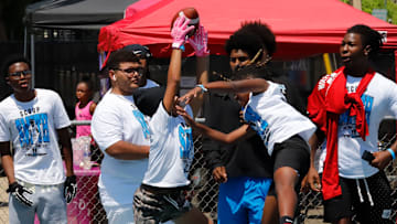 Woodland Hills senior linebacker Zykir "Ziggy" Moore, far right, watches two campers battle for the ball during the Scoop Smith Youth Football Camp in July at the Wolvarena. Smith, seen here with an N.C. State sweater wrapped around his neck, chose to play with the Wolfpack next season.