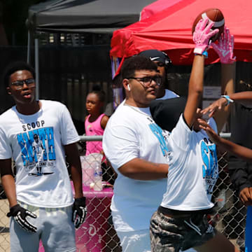 Woodland Hills senior linebacker Zykir "Ziggy" Moore, far right, watches two campers battle for the ball during the Scoop Smith Youth Football Camp in July at the Wolvarena. Smith, seen here with an N.C. State sweater wrapped around his neck, chose to play with the Wolfpack next season.