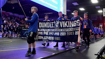 Dundee freshman Braeden Davis carries the Michigan flag, while seniors Christian Killion, Dennis Root, and Jaxon Guinn carry the Dundee Viking banner showing 11 state titles in the grand march at Wings Event Center February 29, 2020. The three seniors were part of the wrestling club at a young age. Dundee won its 12th title beating Richmond 44-18.